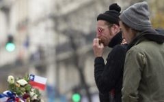 Le chanteur du groupe de rock américain Eagles of Death Metal, Jesse Hughes, (à guache) et le batteur Julian Dorio rendant hommage aux victimes des attentats du 13 novembre à Paris à un mémorial de fortune en face de la salle de concert du Bataclan à Paris le 8 décembre 2015 (Crédit : Miguel Medina / AFP)