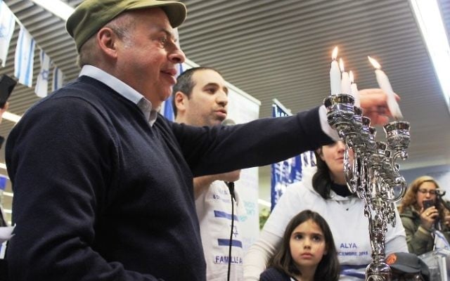 Le président de l'Agence juive, Nathan Sharansky rejoint la famille Ammar pour allumer la troisième bougie de Hanukka pendant une cérémonie d'accueil de dizaines d'immigrants juifs de France en Israël, le 8 décembre 2015. (Crédit : Nathan Roi/Agence juive pour Israël) Le président de l'Agence juive, Nathan Sharansky rejoint la famille Ammar pour allumer la troisième bougie de Hanukka pendant une cérémonie d'accueil de dizaines d'immigrants juifs de France en Israël, le 8 décembre 2015. (Crédit : Nathan Roi/Agence juive pour Israël)
