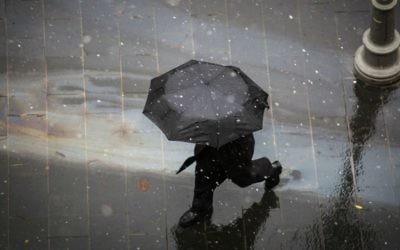 Une passant avec un parapluie dans le centre de Jérusalem tandis qu'une légère neige commence à tomber, le 25 janvier 2016 (Crédit : Hadas Parush / Flash90)