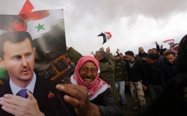 Un volontaire syrien et ses proches brandissent le drapeau national et des portraits du président Bashar el-Assad en célébrant la fin d'un entraînement paramilitaire mené par l'armée syrienne le 22 février 2016. (Crédit : AFP / LOUAI BESHARA) Un volontaire syrien et ses proches brandissent le drapeau national et des portraits du président Bashar el-Assad en célébrant la fin d'un entraînement paramilitaire mené par l'armée syrienne le 22 février 2016. (Crédit : AFP / LOUAI BESHARA)
