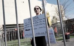 Une femme tient une pancarte contre le rassemblement des ONG de gauche dans le port de Tel Aviv le 5 février 2016. (Crédit : Tomer Neuberg / Flash90