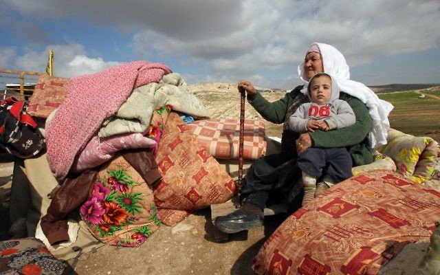 Une femme palestinienne assise avec un enfant à côté de ce qu'ils ont pu récupérer des restes de leur maison après elle a été démolie par les bulldozers israéliens dans la zone militaire de Musafir Jenbach, qui comprend plusieurs villages, au sud de la ville cisjordanienne de Hébron, le 2 février 2016 (Crédit : AFP / HAZEM BADER) Une femme palestinienne assise avec un enfant à côté de ce qu'ils ont pu récupérer des restes de leur maison après elle a été démolie par les bulldozers israéliens dans la zone militaire de Musafir Jenbach, qui comprend plusieurs villages, au sud de la ville cisjordanienne de Hébron, le 2 février 2016 (Crédit : AFP / HAZEM BADER)