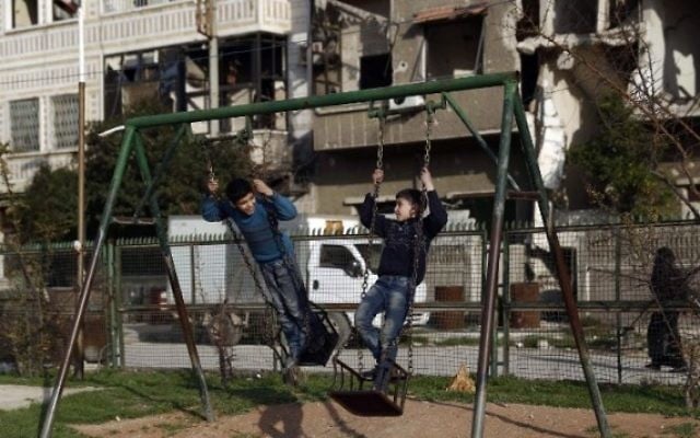 Des enfants syriens jouant à la balançoire dans un parc dans la ville de Douma tenue par les forces rebelles, à l'est de la capitale Damas, le 27 février 2016 (Crédit photo: Sameer Al-Doumy / AFP)