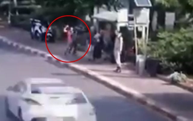 Image d'une caméra de sécurité montrant un terroriste brandissant un couteau (encerclé) et poignardant des Israéliens qui attendent à un arrêt de bus sur le boulevard de Jérusalem à Raanana, le 12 octobre 2015. (Crédit : capture d'écran)