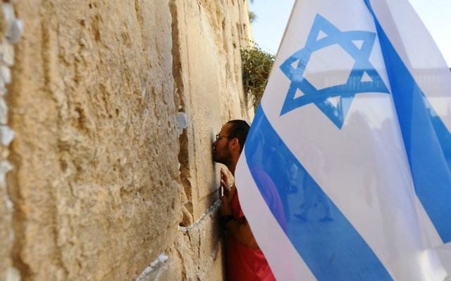 Un homme tient un drapeau israélien au cours d'une marche de soutien à la ville de Jérusalem au mur Occidental le 22 octobre, 2015, après une vague d'attaques terroristes  (Crédit photo: Mendy Hechtman / Flash90)