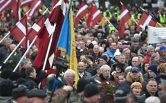 Des vétérans de la légion lettone, une force qui était commandée par les Waffen SS allemands nazis pendant la Seconde Guerre Mondiale, et leurs sympathisants portent des fleurs pendant leur marche vers le monument de la Liberté en Lettonie, à Riga, le 16 mars 2016. (Crédit : AFP/Ilmars Znotins)
