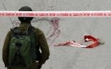 Un soldat de Tsahal se tient près des taches d'un Palestinien qui aurait reçu une balle dans la tête tirée par un soldat alors qu'il gisait blessé sur le sol après avoir poignardé et blessé un soldat israélien à Hébron le 24 mars 2016 (Crédit : AFP / Hazem Bader)