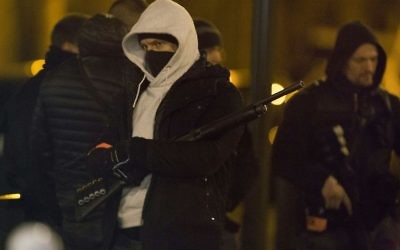 Les policiers montent la garde à l'extérieur d'un bâtiment lors d'un raid dans le quartier du nord-ouest d'Argenteuil à Paris, le 24 mars 2016 (Crédit : AFP / GEOFFROY VAN DER HASSELT)