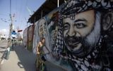 Un garçon palestinien sur son vélo passant devant une fresque de graffitis représentant (de gauche à droite) le fondateur du Front Populaire pour la Libération de la Palestine (FPLP) Georges Habache, le chef spirituel du Hamas, le cheikh Ahmed Yassine et le dirigeant palestinien défunt Yasser Arafat, dans la ville de Gaza, le 21 novembre 2014. (Crédit : Mohammed Abed/AFP)