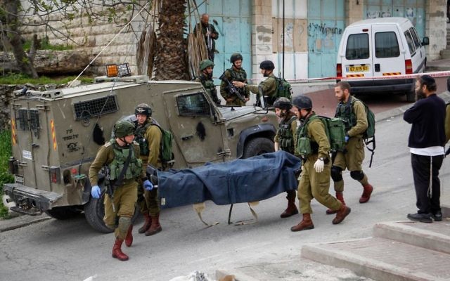 Les soldats israéliens portant le corps d'un Palestinien qui a poignardé un soldat dans la ville de Hébron en Cisjordanie le 24 Mars 2016 (Crédit : Wissam Hashlamon / Flash90) Les soldats israéliens portant le corps d'un Palestinien qui a poignardé un soldat dans la ville de Hébron en Cisjordanie le 24 Mars 2016 (Crédit : Wissam Hashlamon / Flash90)