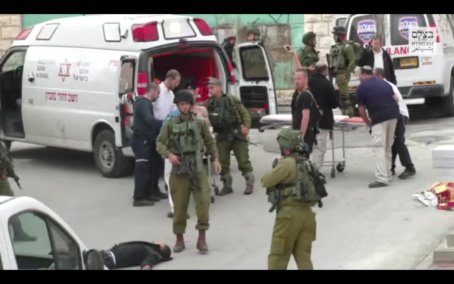 Un soldat de Tsahal passe devant un Palestinien désarmé avant qu'un autre soldat ne tire dans la tête suite à une attaque au couteau à Hébron le 24 mars 2016 (Crédit : Capture d'écran B'Tselem) Un soldat de Tsahal passe devant un Palestinien désarmé avant qu'un autre soldat ne tire dans la tête suite à une attaque au couteau à Hébron le 24 mars 2016 (Crédit : Capture d'écran B'Tselem)