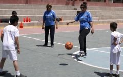 Des professeurs d'éducation physique palestiniennes (en bleu) et des enfants participent à une session d'entraînement organisée par la Fondation du Real Madrid dans une école de l'ONU du camp de réfugiés de Qalandiya, en Cisjordanie, le 25 avril 2016. (Crédit : AFP/ABBAS MOMANI)