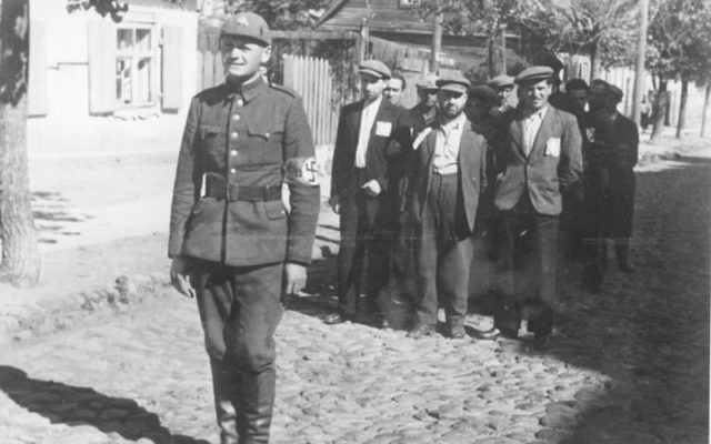 Un policier nazi lituanien avec des prisonniers juifs en juillet 1941 (Crédit : Wikipédia)
