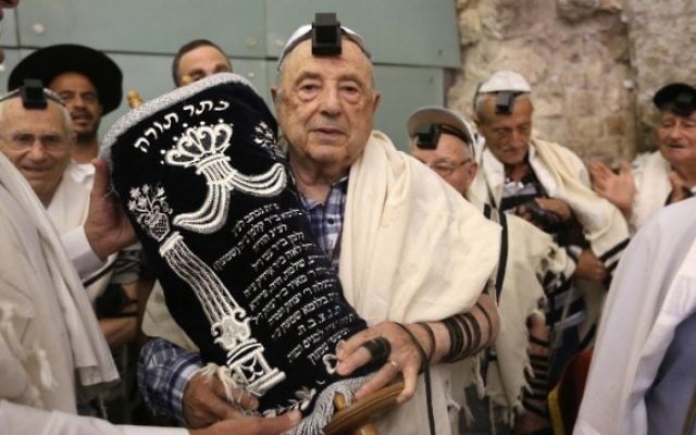 Des dizaines de survivants juifs de l'Holocauste portent talith et tefilin en portant un rouleau de Torah après leur bar mitzvah au mur Occidental, dans la Vieille Ville de Jérusalem, le 2 mai 2016. (Crédit : AFP/Menahem Kahana) Des dizaines de survivants juifs de l'Holocauste portent talith et tefilin en portant un rouleau de Torah après leur bar mitzvah au mur Occidental, dans la Vieille Ville de Jérusalem, le 2 mai 2016. (Crédit : AFP/Menahem Kahana)