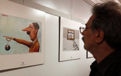Un Iranien observe une caricature montrant Hitler, lors de la deuxième exposition internationale de dessins et caricatures sur l'Holocauste, à Téhéran, le 14 mai 2016. (Crédit : AFP/Atta Kenare)