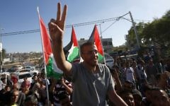 Le journaliste palestinien emprisonné, Mohammed al-Qiq, fait le symbole de la victoire alors qu'il arrive dans son village de Dura, au sud de la Cisjordanie, après avoir été libéré de la prison israélienne de Nafha, le 19 mai 2016 (Crédit : AFP/ HAZEM BADER)