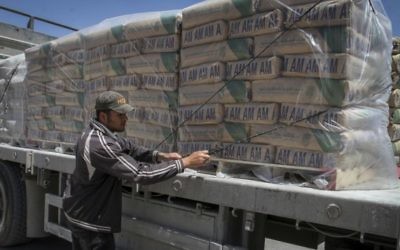 Un Palestinien ajuste les sacs de ciment chargés sur un camion après leur entrée dans le sud de la bande de Gaza depuis Israël, via le poste-frontière Keren Shalom à Rafah, le 29 avril 2015. (Crédit : Abed Rahim Khatib /Flash 90)
