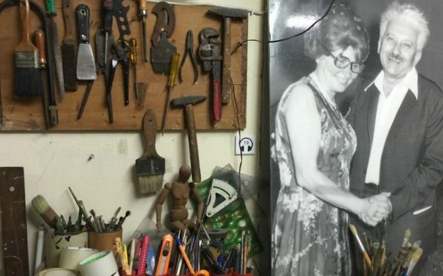 La table à dessin et les outils de Joseph Bau sont toujours en place dans son studio, sous un portrait de lui avec sa femme, Rebecca Tennebaum. (Crédit : Jessica Steinberg/Times of Israel)
