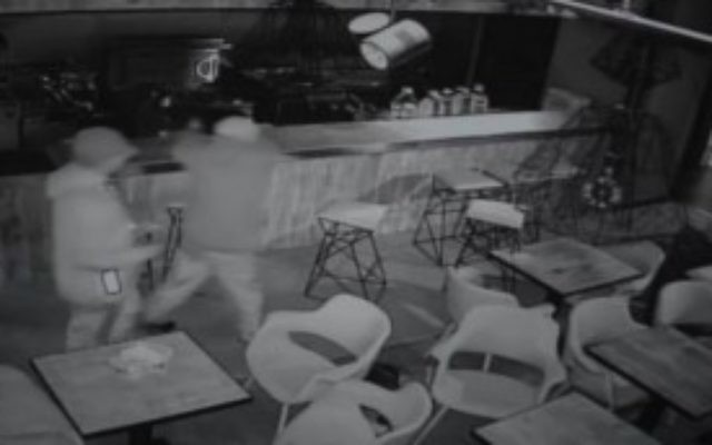 Deux hommes aspergent un restaurant casher d'un liquide avant qu'il ne brûle, à Manchester, en Angleterre, le 6 mai 2016. (Crédit : capture d'écran des vidéos de caméras de sécurité)