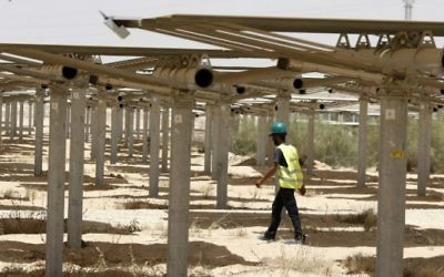 Un ouvrier passe sous les 55 000 miroirs redirigeant la lumière vers la tour solaire Ashalim, dans le désert du Néguev, le 26 mai 2016. (Crédit : Jack Guez/AFP)