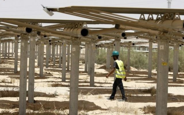 Un ouvrier passe sous les 55 000 miroirs redirigeant la lumière vers la tour solaire Ashalim, dans le désert du Néguev, le 26 mai 2016. (Crédit : Jack Guez/AFP) Un ouvrier passe sous les 55 000 miroirs redirigeant la lumière vers la tour solaire Ashalim, dans le désert du Néguev, le 26 mai 2016. (Crédit : Jack Guez/AFP)