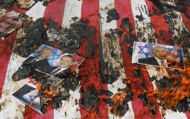 Portrait du roi de Bahreïn Hamad (en haut à gauche), du Premier ministre israélien Benjamin Netanyahu et du président turc Recep Tayyip Erdogan sur un drapeau américain en flammes pendant une manifestation de la Journée al-Quds [Jérusalem] à Téhéran, le 1er juillet 2016. (Crédit : Atta Kenare/AFP)