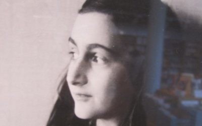 Photographie prise dans la librairie de la maison d'Anne Frank, avec sa photo et des copies traduites de son journal en arrière-plan. (Crédit : Matt Lebovic/Times of Israël)