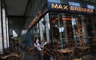 Une femme nettoie les tables au restaurant Max Brenner du marché Sarona, dans le centre de Tel Aviv, le 9 juin 2016, au lendemain matin de l'attaque terroriste qui s'y est déroulée (Crédit : Miriam Alster/Flash90)