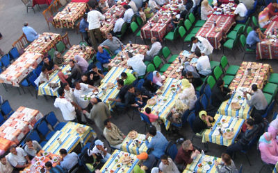 Des musulmans attentent le coucher du soleil pour commencer le repas de l'iftar, pendant le mois de Ramadan, au Caire, en 2005. (Crédits : Wiki Commons)