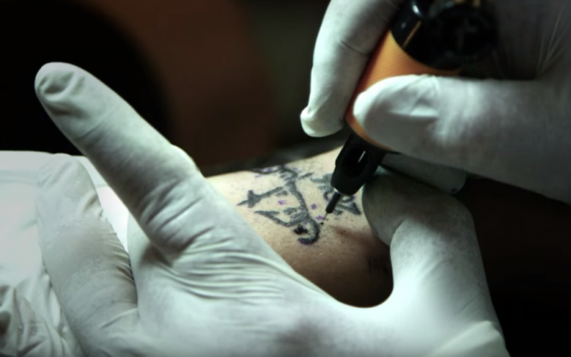 Un tatouage religieux en cours de réalisation par Walid Ayash, à Bethléem. (Crédits : capture d'écran YouTube / AFP TV) Un tatouage religieux en cours de réalisation par Walid Ayash, à Bethléem. (Crédits : capture d'écran YouTube / AFP TV)