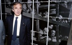 Elie Wiesel, auteur, prix Nobel de la Paix et survivant de la Shoah, devant une photo de lui et d'autres détenus au camp de concentration de Buchenwald en 1945, pendant sa visite au musée et mémorial de la Shoah de Yad Vashem, à Jérusalem, le 18 décembre 1986. (Crédit : AFP/Sven Naxkstrand)