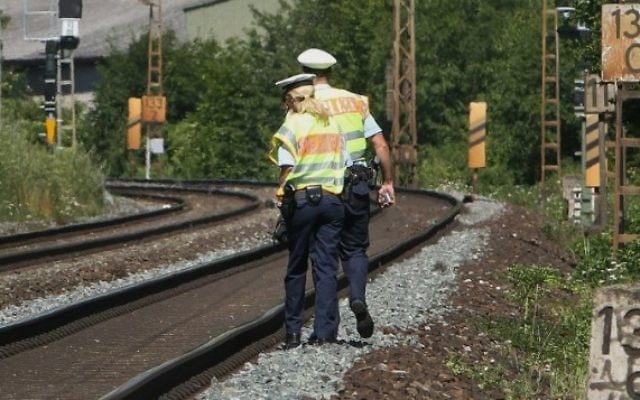 Des policiers marchent le long des voies ferrées à Wurzburg, le 19 juillet 2016, au-delà de l'attaque à la hache dans un train par un jeune réfugié afghan. (Crédit : AFP/Daniel Roland)