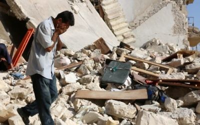 Un Syrien réagit alors que les secouristes recherchent des victimes sous les décombres d'un bâtiment effondré suite à une frappe aérienne sur le quartier rebelle de Sakhur dans la ville du nord, Alep, le 19 juillet, 2016 (Crédit : AFP / Thaer Mohammed)