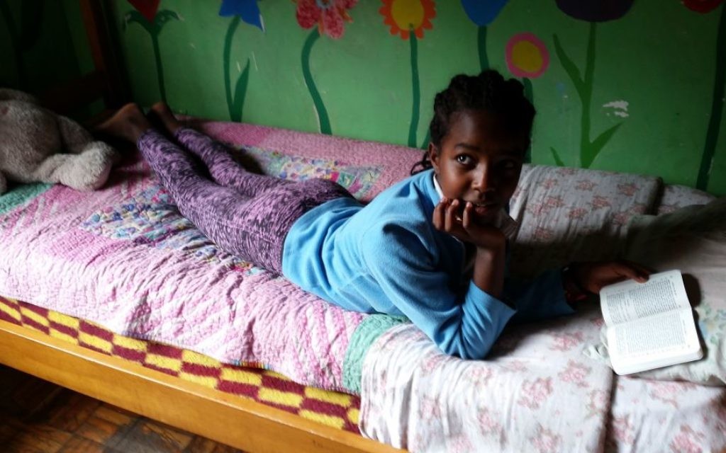 Une fille lit la Bible dans son lit au Centre d'Addis-Abeba AHOPE pour les orphelins séropositifs, le 7 juillet 2016 (Crédit : Raphael Ahren / Times of Israel) Une fille lit la Bible dans son lit au Centre d'Addis-Abeba AHOPE pour les orphelins séropositifs, le 7 juillet 2016 (Crédit : Raphael Ahren / Times of Israel)