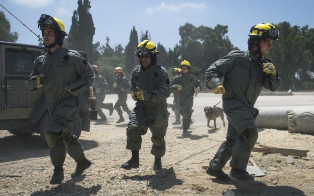 Des soldats des unités de recherche et sauvetage du Commandement de la Défense passive de l'armée israélienne courent sur la scène d'une fausse frappe de roquette pendant un exercice à grande échelle, à Zikim, près de la frontière de la bande de Gaza, le 3 juillet 2016. (Crédit : unité des porte-paroles de l'armée israélienne) Des soldats des unités de recherche et sauvetage du Commandement de la Défense passive de l'armée israélienne courent sur la scène d'une fausse frappe de roquette pendant un exercice à grande échelle, à Zikim, près de la frontière de la bande de Gaza, le 3 juillet 2016. (Crédit : unité des porte-paroles de l'armée israélienne)