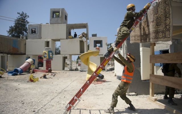Des soldats des unités de recherche et sauvetage du Commandement de la Défense passive de l'armée israélienne nettoient des débris d'une fausse frappe de roquette pendant un exercice à grande échelle, à Zikim, près de la frontière de la bande de Gaza, le 3 juillet 2016. (Crédit : unité des porte-paroles de l'armée israélienne) Des soldats des unités de recherche et sauvetage du Commandement de la Défense passive de l'armée israélienne nettoient des débris d'une fausse frappe de roquette pendant un exercice à grande échelle, à Zikim, près de la frontière de la bande de Gaza, le 3 juillet 2016. (Crédit : unité des porte-paroles de l'armée israélienne)