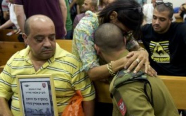 Le soldat de l'armée israélienne Elor Azaria, qui est jugé pour avoir abattu un attaquant palestinien désarmé, dans les bras d'une personne le soutenant au tribunal militaire de Jaffa, le 5 juillet 2016 (Crédit : Flash90) Le soldat de l'armée israélienne Elor Azaria, qui est jugé pour avoir abattu un attaquant palestinien désarmé, dans les bras d'une personne le soutenant au tribunal militaire de Jaffa, le 5 juillet 2016 (Crédit : Flash90)