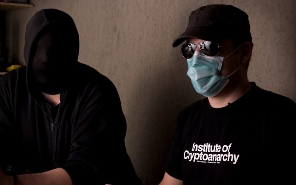 Des crypto-anarchistes masqués dans une scène de "Down the Deep, Dark Web. (Crédit : autorisation)