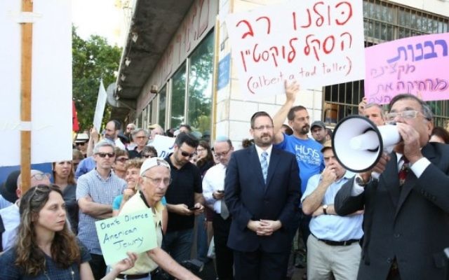 Le grand rabbin d'Efrat Shlomo Riskin parle dans un mégaphone, le 6 juillet 2016, lors d'une manifestation devant les bureaux du grand rabbin de Jérusalem, en soutien aux conversions du rabbin new-yorkais Haskel Lookstein, sous l’œil attentif du chef de l'Agence juive Natan Sharansky et de l'ancien député Dov Lipman (Crédit : Ezra Landau) Le grand rabbin d'Efrat Shlomo Riskin parle dans un mégaphone, le 6 juillet 2016, lors d'une manifestation devant les bureaux du grand rabbin de Jérusalem, en soutien aux conversions du rabbin new-yorkais Haskel Lookstein, sous l’œil attentif du chef de l'Agence juive Natan Sharansky et de l'ancien député Dov Lipman (Crédit : Ezra Landau)