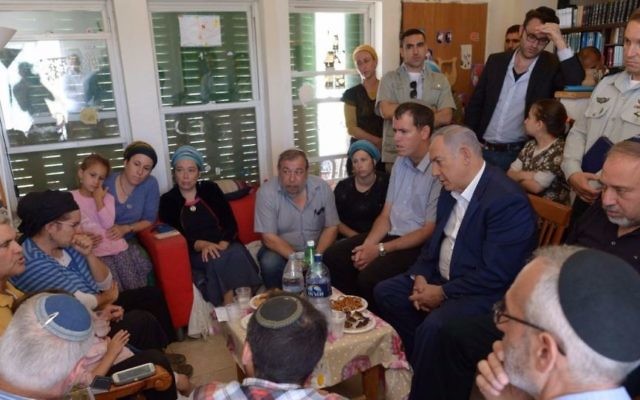 Le Premier ministre Benjamin Netanyahu (assis, deuxième à droite) et le ministre de la Défense Avigdor Liberman (assis, à droite) se sont joints à la famille et aux proches chez Hallel Yaffa Ariel à Kiryat Arba, le 1er juillet 2016, un jour après qu'elle a été poignardée à mort dans son lit. (Crédit : Amos Ben Gershom/GPO)
