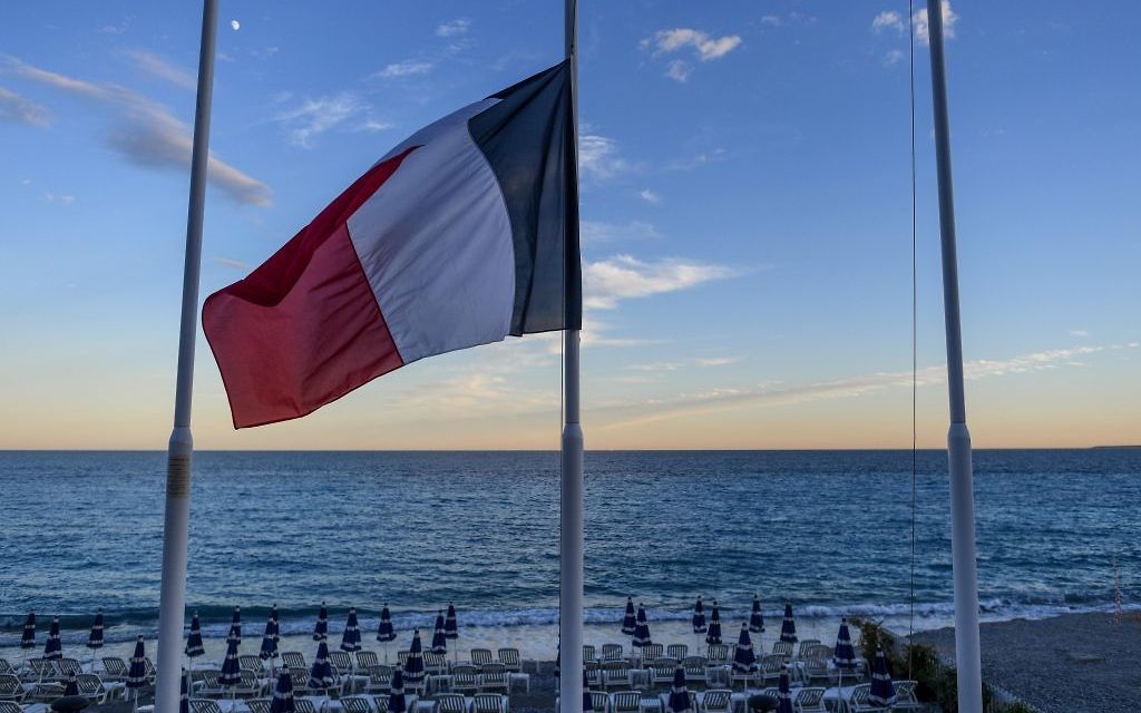 Le drapeau français en berne devant une plage vide de la Promenade des Anglais à Nice, au lendemain d'un attentat qui a fait 84 morts, le 15 juillet 2016. (Crédit : David Ramos/Getty Images via JTA)