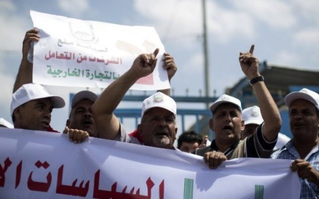 Des hommes d'affaires et des marchands palestiniens manifestant pour protester contre la suspension par Israël de leurs permis de voyage les autorisant à se rendre en Israël et en Cisjordanie, à Beit Hanun, près du poste-frontière d'Erez, dans le nord de la bande de Gaza, le 15 août 2016. (Crédit : AFP/Mahmud Hams)