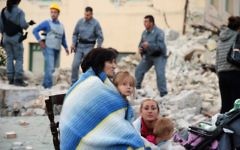 Des victimes assises parmi les décombres des maisons après un fort tremblement de terre à Amatrice, en Italie, le 24 août 2016. (Crédit : AFP/Filippo Monteforte)