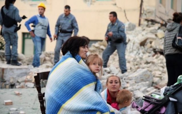 Des victimes assises parmi les décombres des maisons après un fort tremblement de terre à Amatrice, en Italie, le 24 août 2016. (Crédit : AFP/Filippo Monteforte)