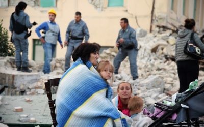 Les victimes assis dans les décombres d'une maison après un fort tremblement de terre qui a frappé Amatrice, Italie, le 24 août 2016 (Crédit : AFP / FILIPPO MONTEFORTE)