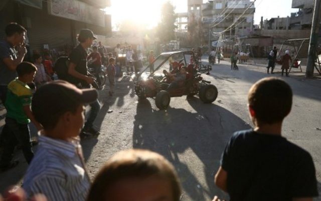 Des enfants syriens jouent dans la rue au troisième jour de l'Aïd al-Adha, dans la ville contrôlée par les rebelles de Hamouria, près de Damas, au deuxième jour d'un cessez-le-feu, le 14 septembre 2016. (Crédit : AFP/Abd Doumany) Des enfants syriens jouent dans la rue au troisième jour de l'Aïd al-Adha, dans la ville contrôlée par les rebelles de Hamouria, près de Damas, au deuxième jour d'un cessez-le-feu, le 14 septembre 2016. (Crédit : AFP/Abd Doumany)