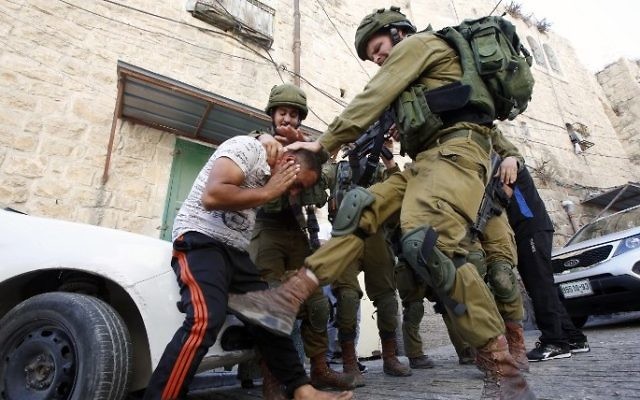 Un soldat israélien donne un coup de pied à un Palestinien pendant son arrestation à Hébron, en Cisjordanie, le 20 septembre 2016. (Crédit : AFP/Hazem Bader) Un soldat israélien donne un coup de pied à un Palestinien pendant son arrestation à Hébron, en Cisjordanie, le 20 septembre 2016. (Crédit : AFP/Hazem Bader)