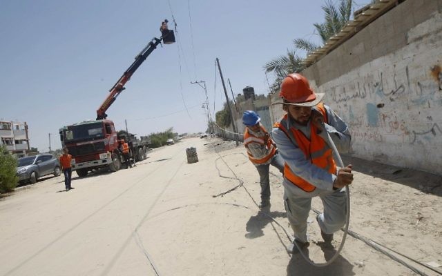 Des employés de la compagnie d'électricité palestinienne traînent une ligne électrique, à Rafah, dans le sud de la bande de Gaza, le 6 août 2014. (Crédit : Said Khatib/AFP) Des employés de la compagnie d'électricité palestinienne traînent une ligne électrique, à Rafah, dans le sud de la bande de Gaza, le 6 août 2014. (Crédit : Said Khatib/AFP)