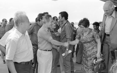 Shimon Peres, alors ministre de la Défense, et l'ancien Premier ministre Yitzhak Rabin, rencontrent les otages libérés d'Entebbe à leur atterrissage en Israël, le 4 juillet 1976. (Crédit : Uri Herzl Tzchik/unité des porte-paroles de l'armée israélienne/archives du ministère de la Défense)