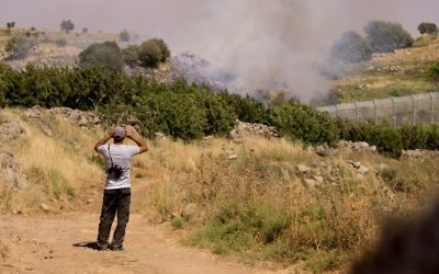 Un Druze regarde les bombardements entre les forces syriennes depuis la partie israélienne du plateau du Golan, le 16 juin 2015. (Crédit : Basel Awidat/Flash90)